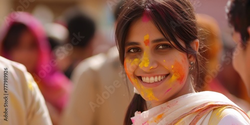  A woman with colorful Holi festival powder on her face smiles warmly, showcasing the festive spirit and cultural joy of the event.