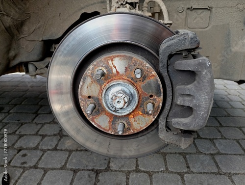 Car wheel removed. Bolts that hold the car wheel and brake pads in the calipers. Car suspension maintenance. Wheel replacement.