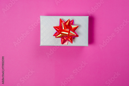 Topview of a giftbox with ribbon on pink background. Copypace