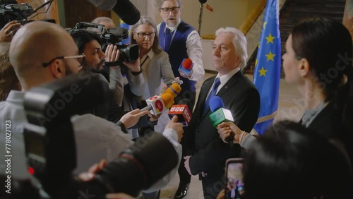 EU representative answers press questions and gives interview for TV breaking news. Senior consul surrounded by crowd of journalists. Political speech during press conference. State of the nation. photo