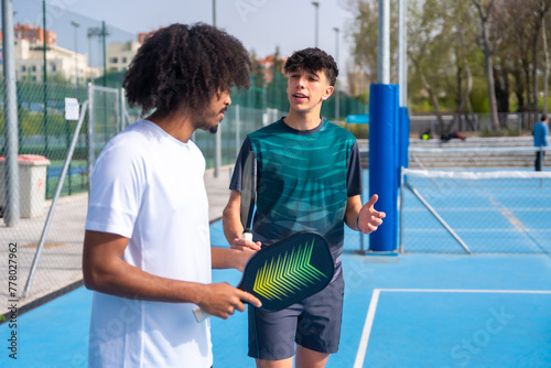 Instructor talking to a young african man playing pickleball