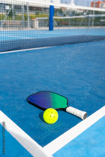 Racket and yellow pickleball ball on a court