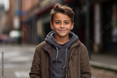 A young boy wearing a brown jacket and a gray hoodie is smiling