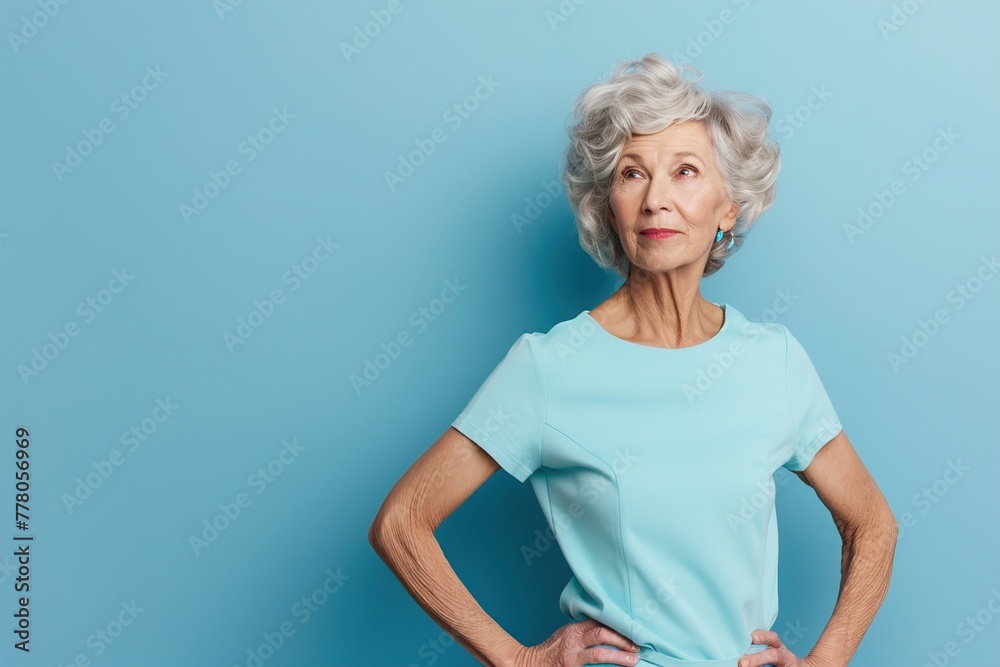 A woman in a blue shirt stands with her arms crossed and looks to her left A woman in a blue shirt stands with her arms crossed and looks to her left