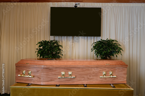A wooden coffin with brass handles in a funeral chapel.