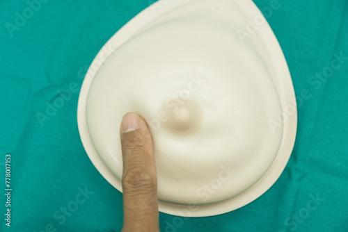 Breast implants for teaching breast self-examination.Close up fingure touching breast model for training breast checkup on green surgery wrap set background.