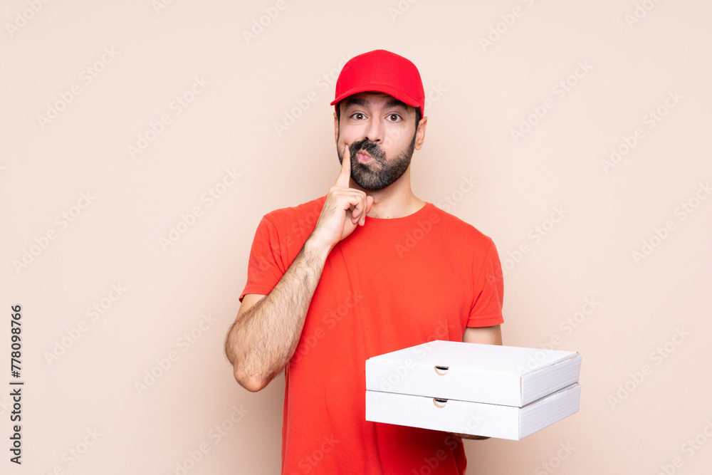 Young man holding a pizza over isolated background Looking front Young man holding a pizza over isolated background Looking front