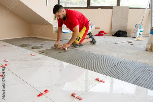 Ceramic white floor tiles laid over adhesive with a tile leveling system