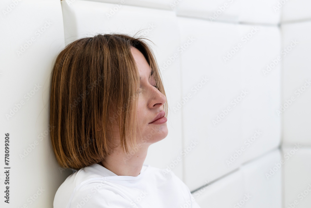 Young frustrated girl in a straitjacket is in an isolated white room in a mental hospital Young frustrated girl in a straitjacket is in an isolated white room in a mental hospital