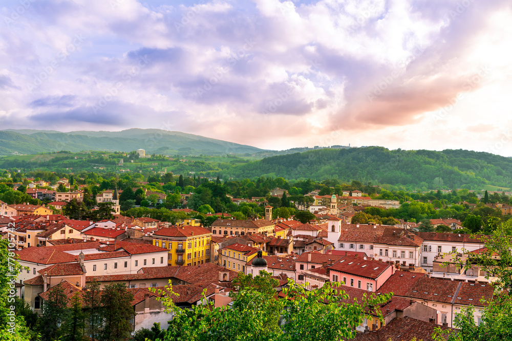 travel summer view from hill to a nice european town with amazing buildings, green hills and mountains with amazing cloudy evening sky on background