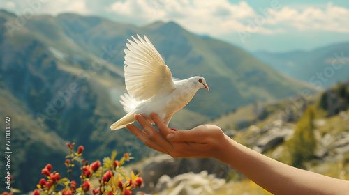 Image of hand releasing white pigeon against natural scenery, mountains, and sky with blurred style. Freedom concept and international day of peace. photo