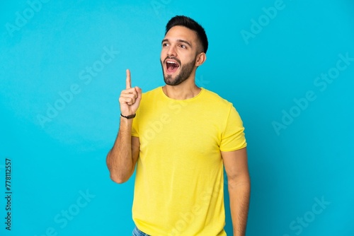 Young caucasian man isolated on blue background intending to realizes the solution while lifting a finger up