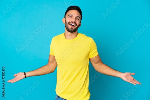 Young caucasian man isolated on blue background happy and smiling
