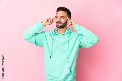 Young caucasian man isolated on pink background having doubts and thinking