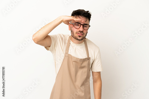 Restaurant waiter caucasian man isolated on white background looking far away with hand to look something © luismolinero