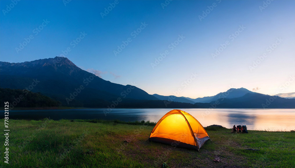morning twilight scene of mountain with camping tent and light up at the lake shore