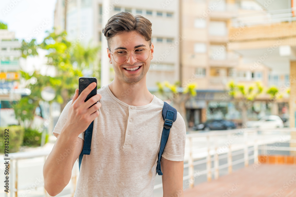 Young handsome man using mobile phone at outdoors with happy expression