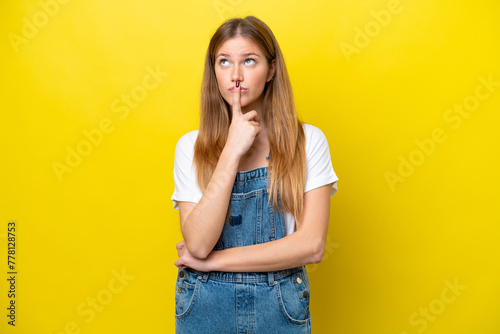 Young caucasian woman isolated on yellow background having doubts while looking up