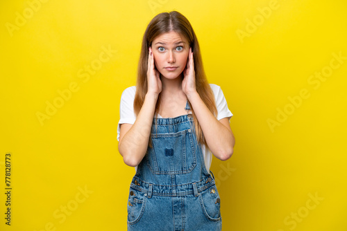 Young caucasian woman isolated on yellow background frustrated and covering ears