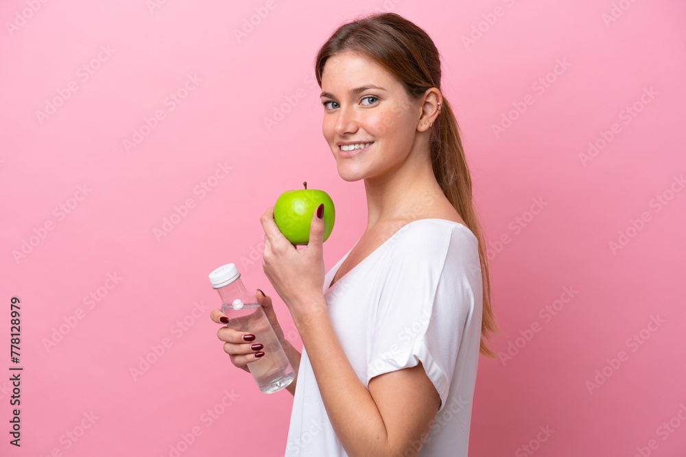 Young caucasian woman isolated on pink background with an apple and with a bottle of water Young caucasian woman isolated on pink background with an apple and with a bottle of water