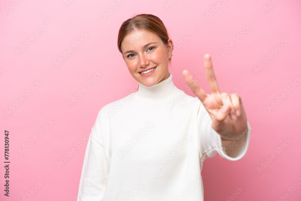 Young caucasian woman isolated on pink background smiling and showing victory sign Young caucasian woman isolated on pink background smiling and showing victory sign