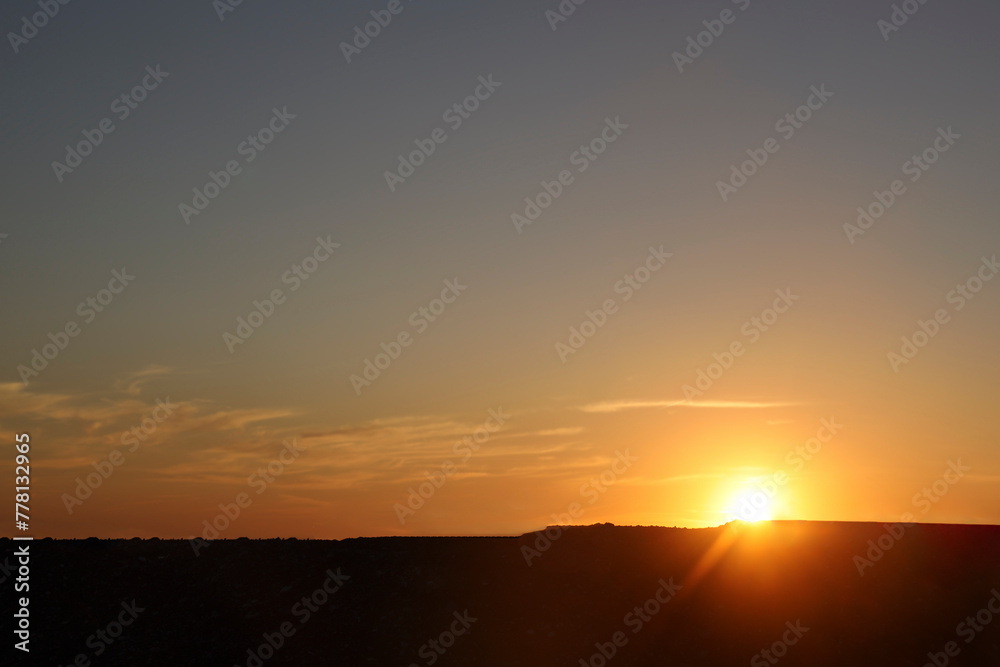 Sky with a Black Mountain Silhouette. Play of Light and Shadow. sun set above horizon line. Sunset above horizon line with sun setting down behind mountains and sun rays. mountains peak. sun beam