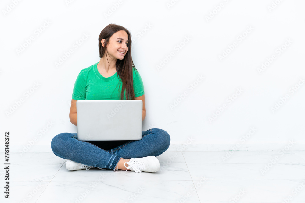Young Ukrainian woman with a laptop sitting on floor looking side Young Ukrainian woman with a laptop sitting on floor looking side