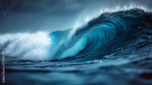 a large wave in the middle of a body of water with a dark blue sky in the background and a white foamy wave in the middle of the water. © Mikus