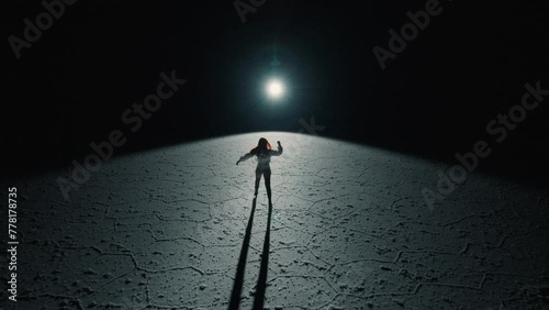 Salt Flats of Bolivia and a redhead dancer walking towards light at night photo