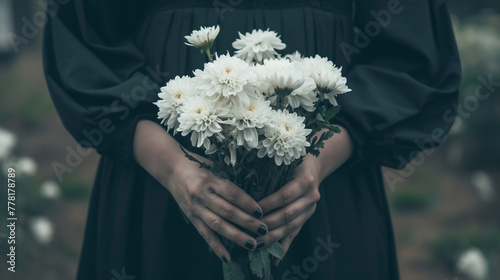 喪服を着て白い菊の花を手に持つ女性の手元のクローズアップ写真 photo