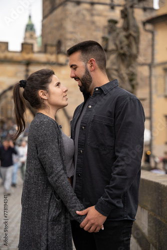 Young couple in love looking at each other while posing on Charles Bridge in Prague. © Jenni Ventura Martil