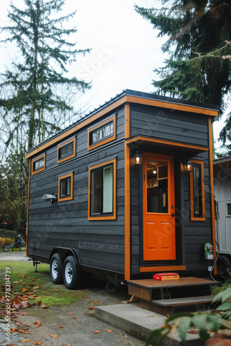 A small, black and orange cabin is parked in a wooded area