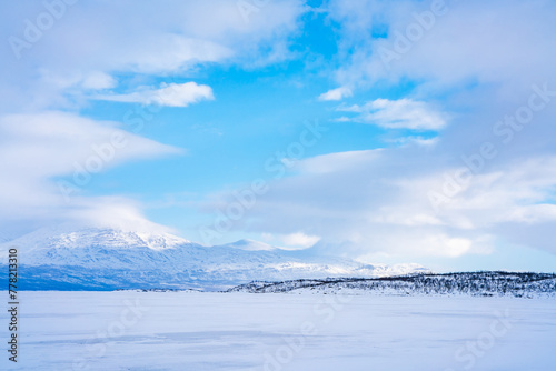 Valokuva Frozen lake Tornetrask and snow covered mountains around Abisko, Sweden