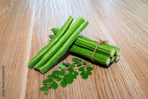 Moringa Oleifera or drumstick vegetable with leaves on wooden background photo