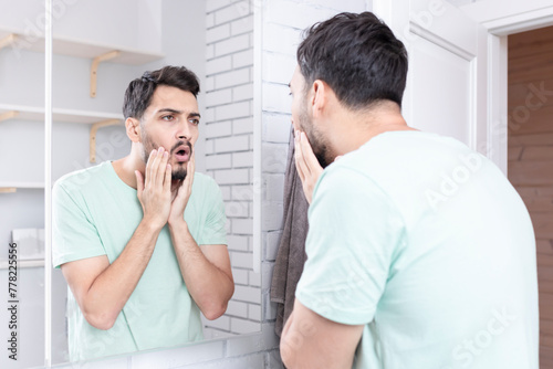 Young funny man looking at the mirror after morning routine in the bathroom 