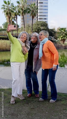 Small group of mature women taking a selfie in a park. Senior tourists having fun outside.
