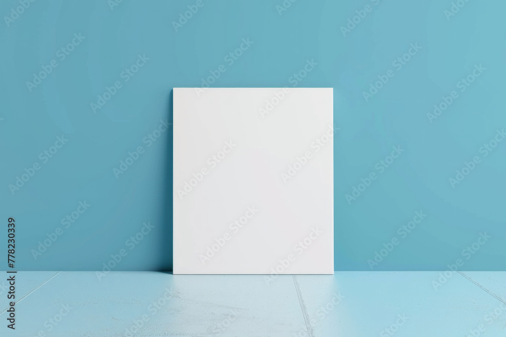 A white blank canvas hanging on a clean blue color wall A white blank canvas hanging on a clean blue color wall