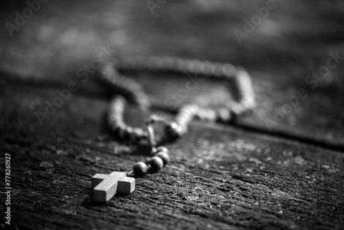 Rosary on an old wooden table illuminated by the sun (ID: 778261927)