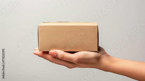 A simple brown cardboard box rests on top of a hand. Small box with natural texture and no additional finishing. The image can be used for advertisements for products that care about sustaiArte com IR