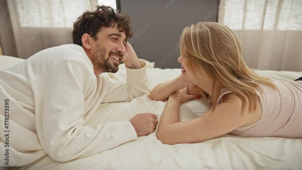 A loving couple, a man and woman, intimately converse while lying on a bed indoors, evoking a sense of togetherness. A loving couple, a man and woman, intimately converse while lying on a bed indoors, evoking a sense of togetherness.