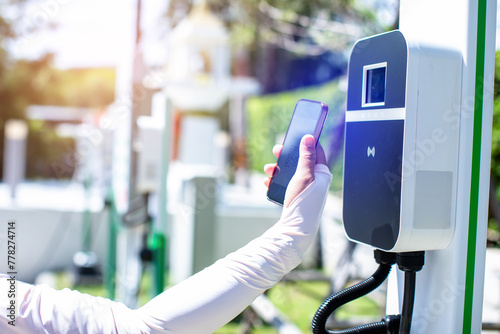 EV Driver use smartphone to scan QR Code on electric vehicle charging stations to pay for electricity. The concept of QR scanning payment instead of cash.