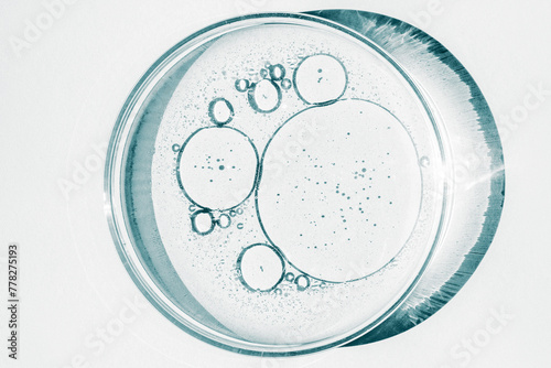 Petri dish. Petri's cup with liquid. Chemical elements, oil, cosmetics. Gel, water, molecules, viruses. Close-up. On a white background.