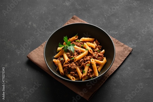 Penne pasta with minced meat, tomato sauce and greens