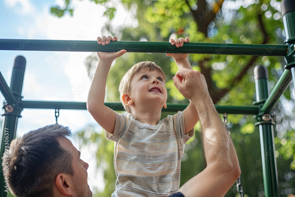 Little positive boy at the monkey bars and his father watching and helping Little positive boy at the monkey bars and his father watching and helping
