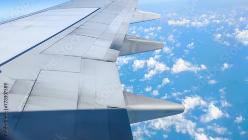 Time lapse The view from the airplane window. Flying above the blue sky with moving clouds. Traveling on airplane at clear weather day.
