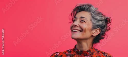 a woman smiling with grey hair on a pink background, empty space for text