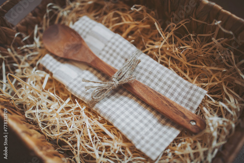 wooden spoon and kitchen towel in a box with straw. Cooking concept. empty wooden spoon on the natural background. Kitchen and cooking accessories. Eco-friendly products. A gift set for the hostess.