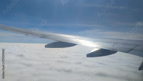 The view from the airplane window. Flying above the blue sky with moving clouds. Traveling on airplane at clear weather day.