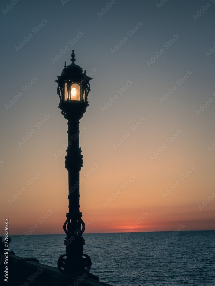 Sunset and a lonely lamppost at the avenida Campo del Sur in Cadiz Spain