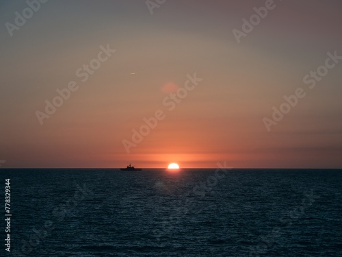 A military ship of the Spanish Navy sailing on the horizon during sunset